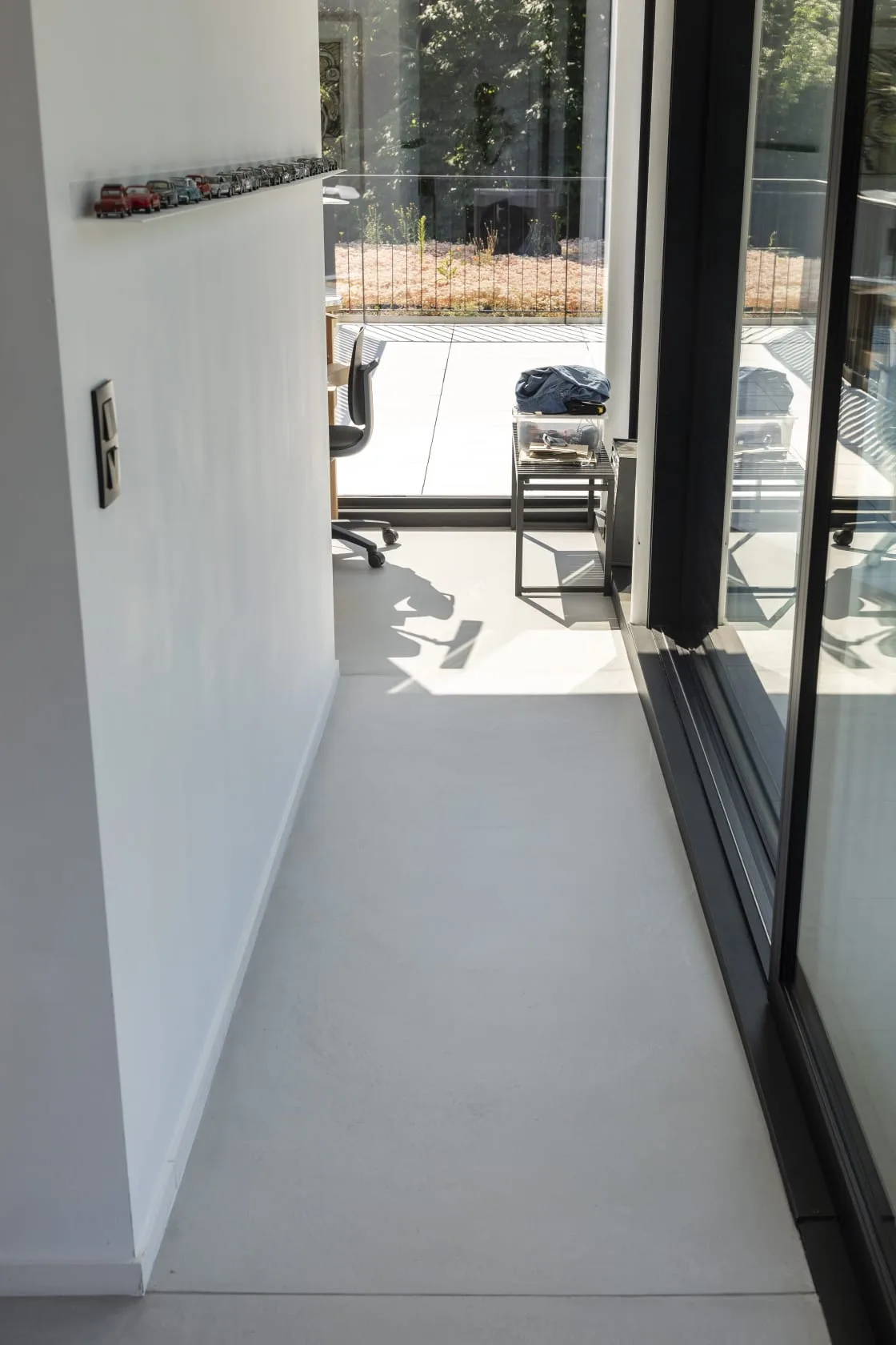 Sol en béton ciré clair dans un couloir menant à un bureau avec baie vitrée coulissante
