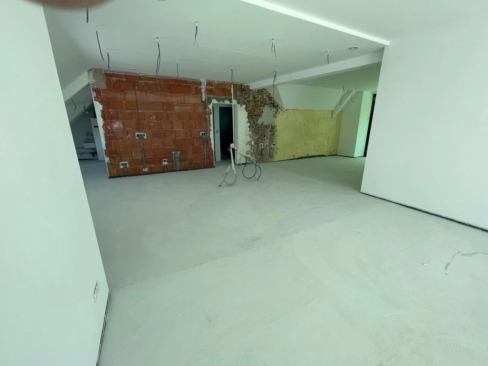 Piece en renovation avec sol en beton cire et mur en briques apparentes avant finition
